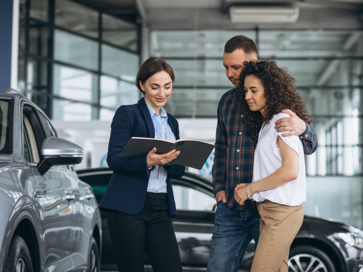 vendedor apresentando contrato para um jovem casal em locddora de carros