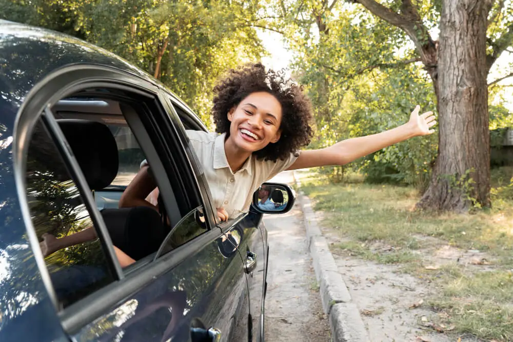 Mulher sorridente no banco de passageiro de carro alugado