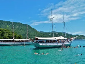 Barco ancorado e turistas em água cristalina de Angra dos Reis