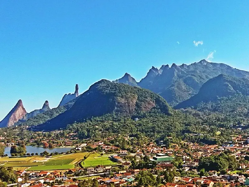 Cidade de Teresópolis com a Serra dos Órgãos e o Dedo de Deus ao fundo.