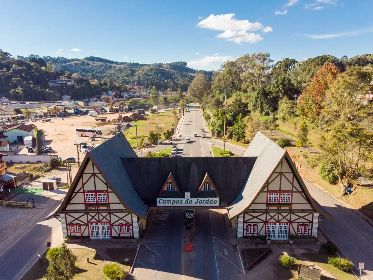 Pórtico de entrada ao estilo enxaimel, arquitetura típica alemã, com o nome 'Campos do Jordão' centralizado sobre a pista.