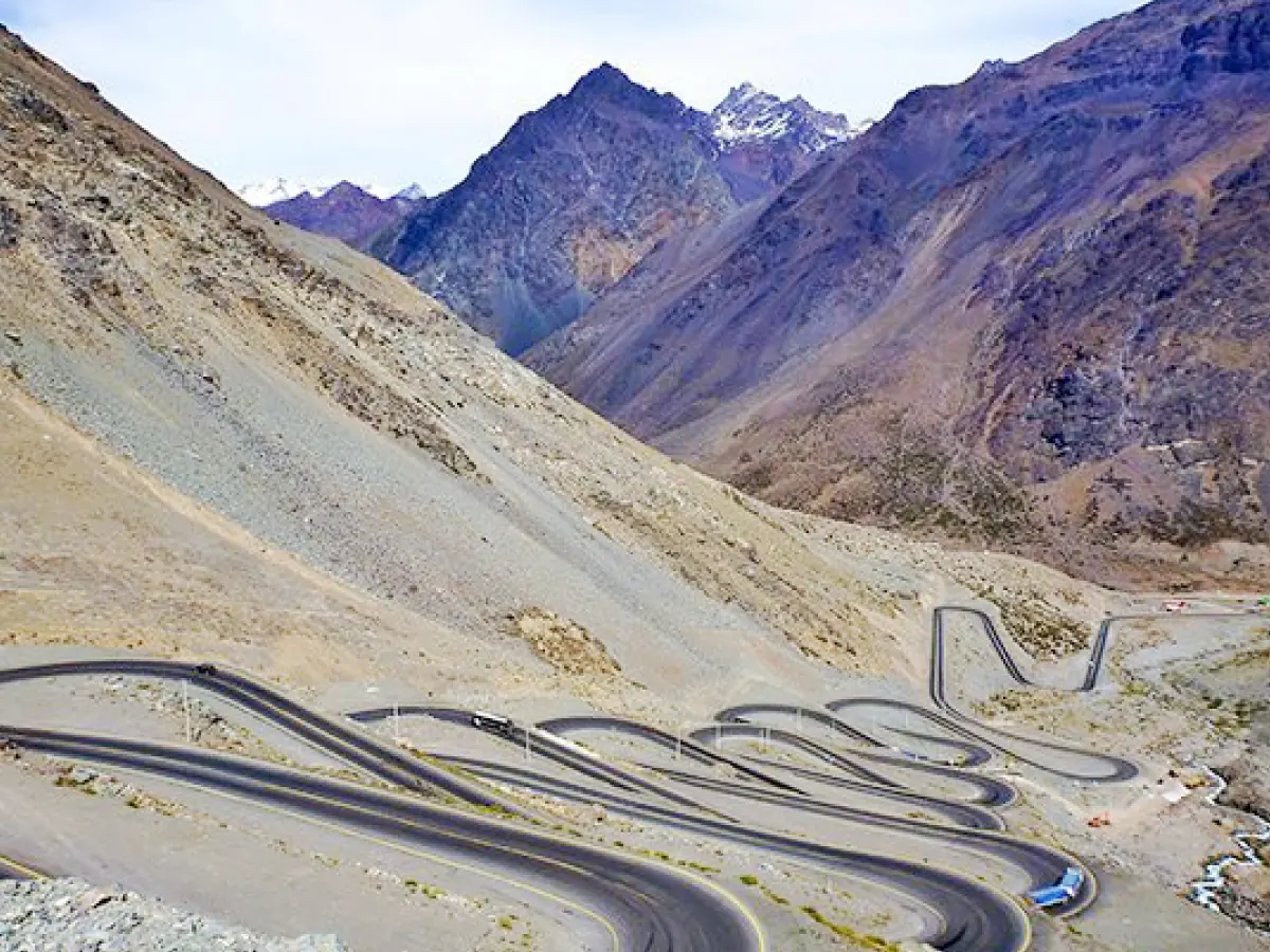 As montanhas da Cordilheira dos Andes em época sem neve, somente no topo, e a grandeza da Estrada Los Caracoles, asfaltada sobre terreno árido, praticamente sem movimento de veículos no trecho com muitas curvas sinuosas.