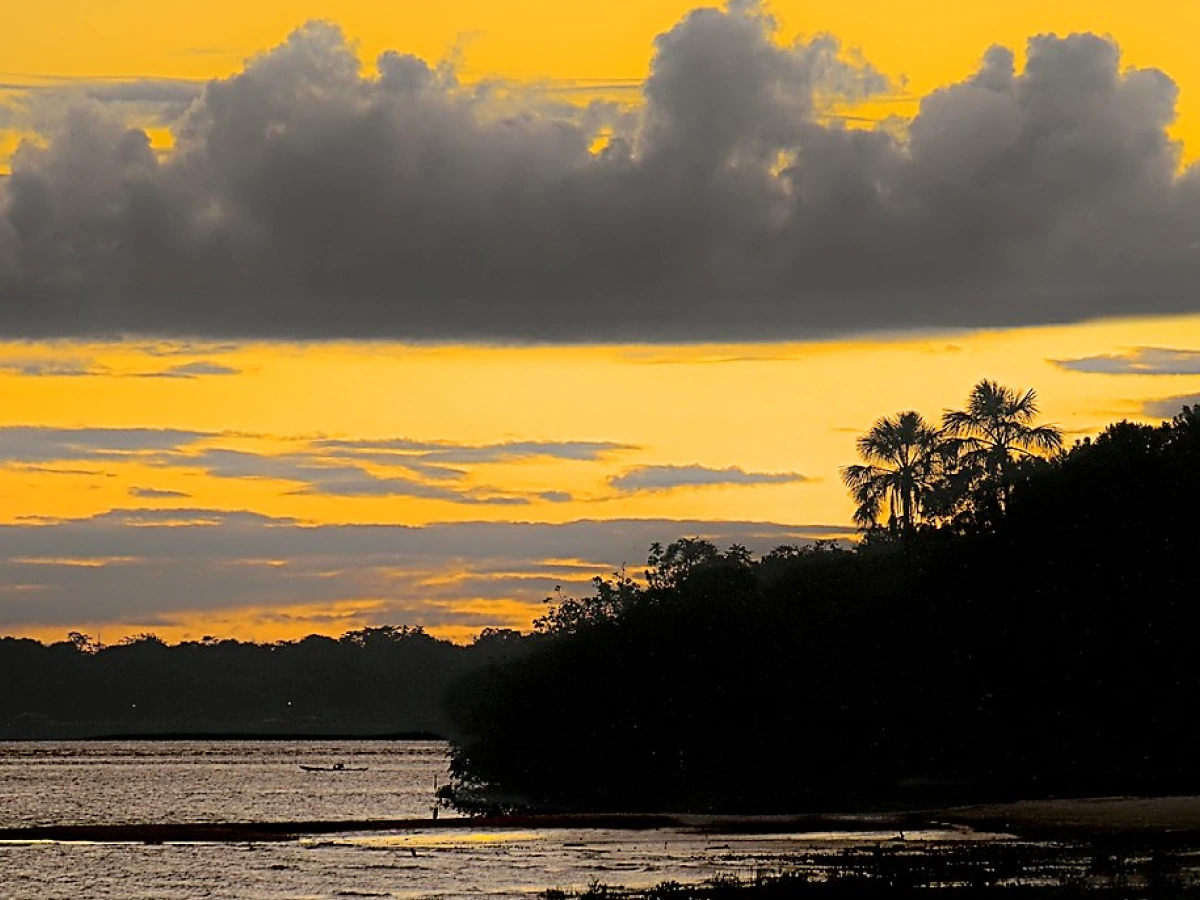 Entardecer com nuvens contrastantes evidencia as águas da praia da Fazendinha e sua vegetação exuberante.