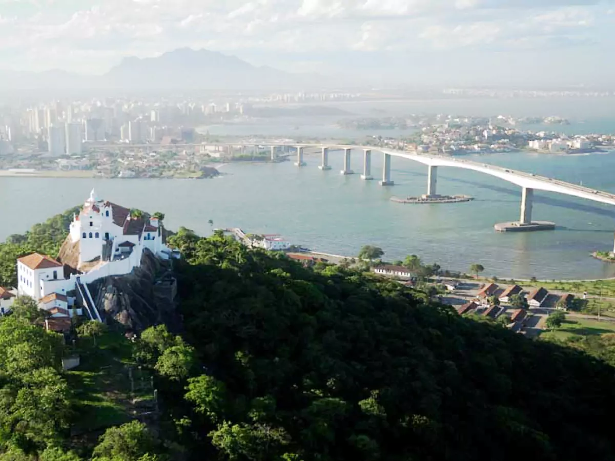 Ponte Deputado Darcy Castello de Mendonça, popularmente conhecida como Terceira Ponte, ligando Vitória (ES) à região metropolitana. Atravessa a Baía de Vitória, tendo na paisagem um morro com muito verde e construção no topo, além de prédios ao fundo, do outro lado da travessia.