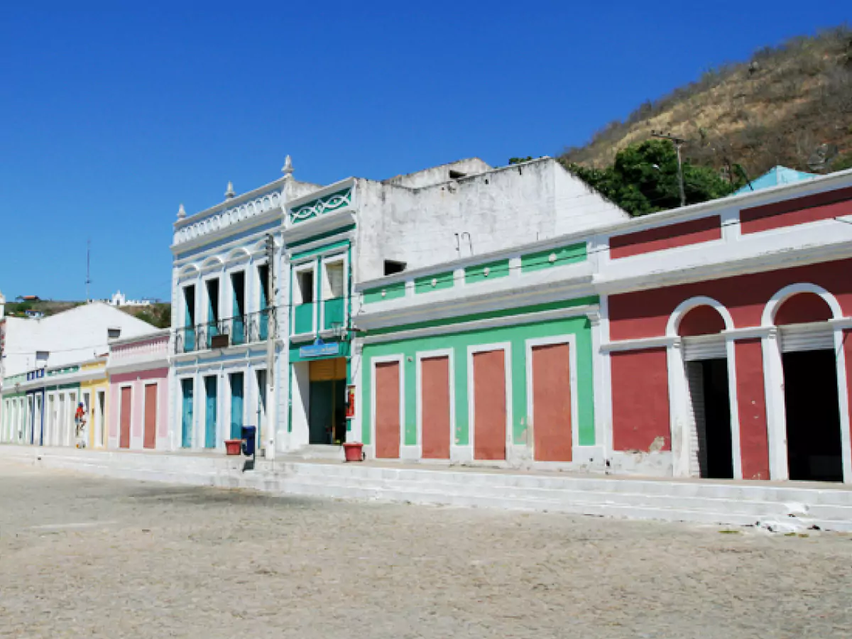 Casarões coloniais no centro histórico de Piranhas. Rua tranquila e o céu azul contrastando com as construções coloridas.