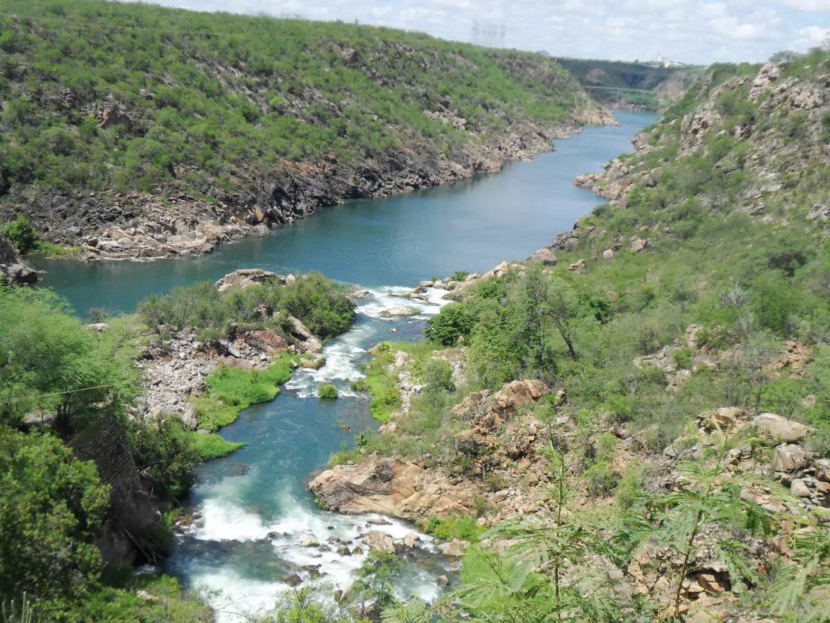 Trecho do Rio São Francisco em Paulo Afonso, com quedas d'água e seus paredões repletos de vegetação.