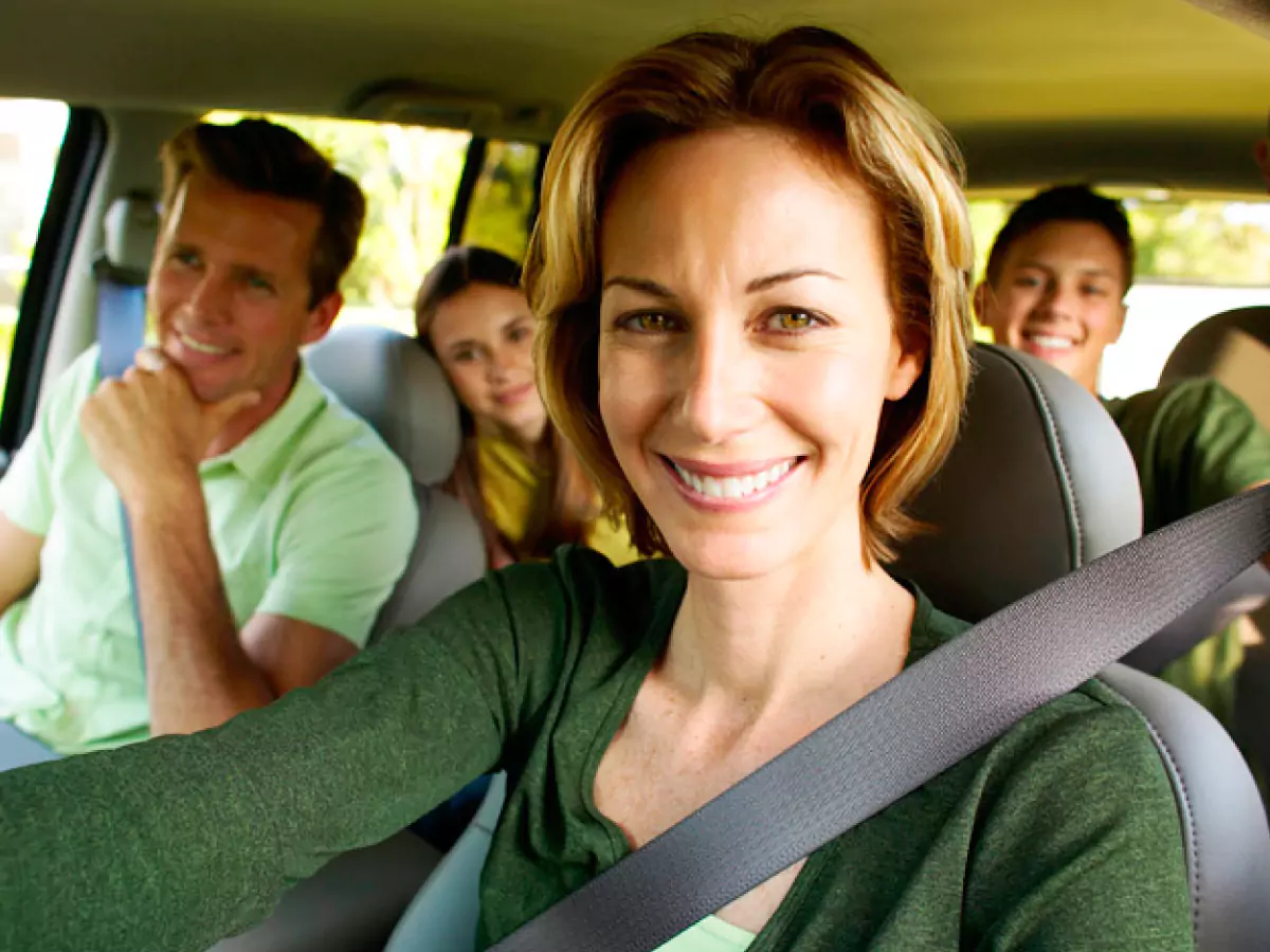 Família está dentro de um carro, indo viajar. Eles estão contentes.