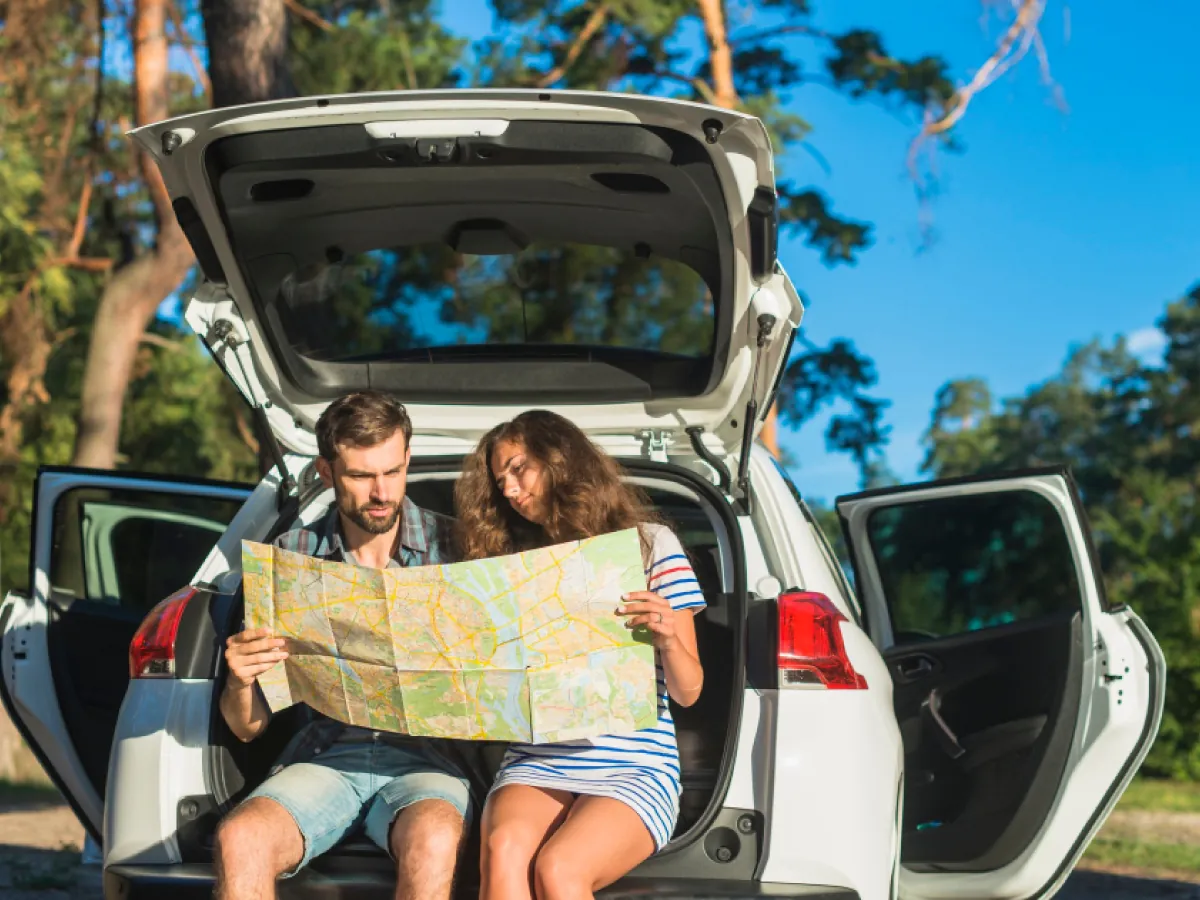 casal jovem em viagem de carro olhando um mapa