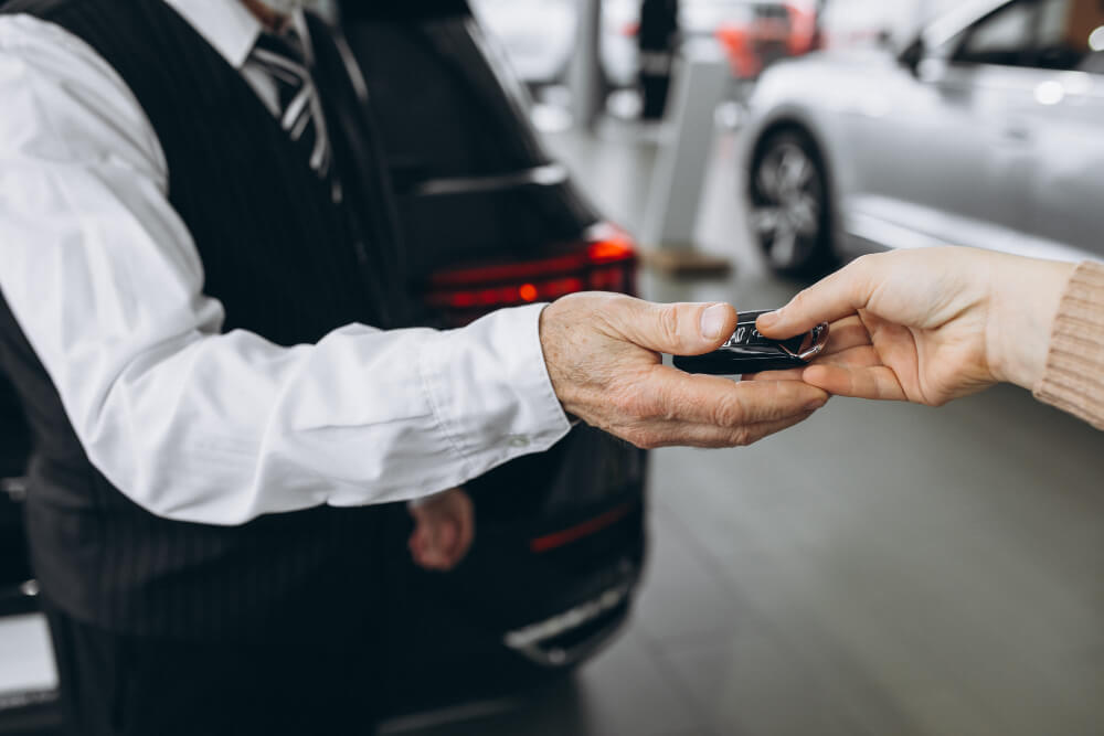 O atendente de uma locadora de veículos recebe em sua mão a chave do carro alugado pelo homem