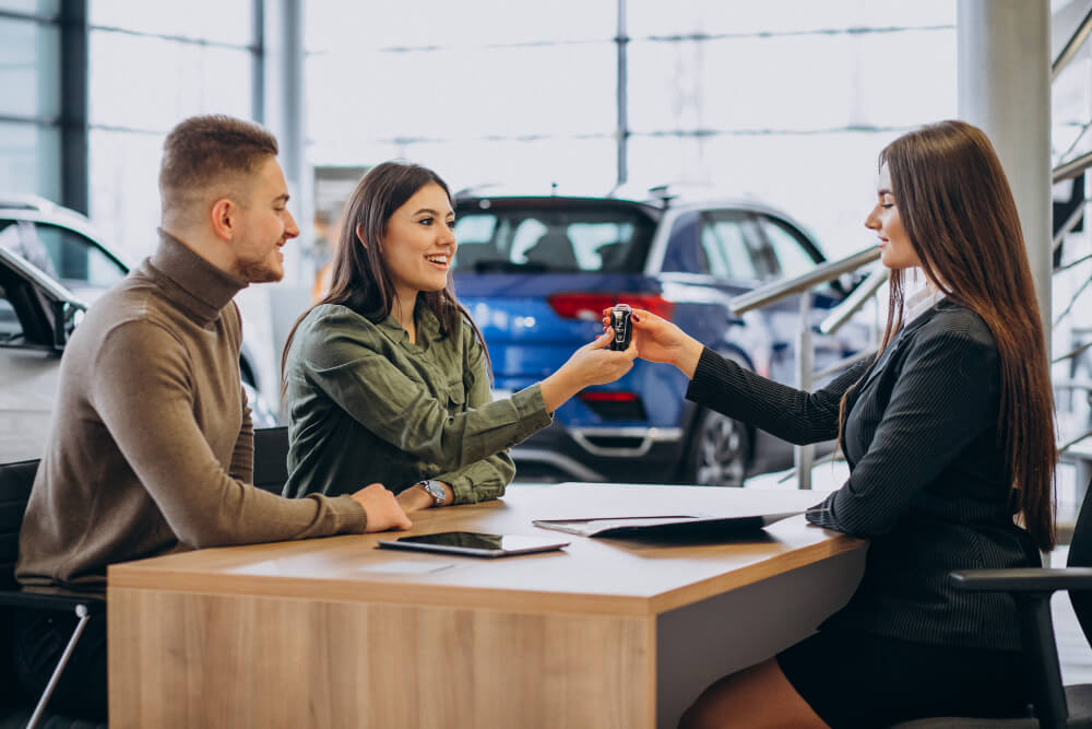 Um casal jovem a falar com um vendedor numa loja de automóveis