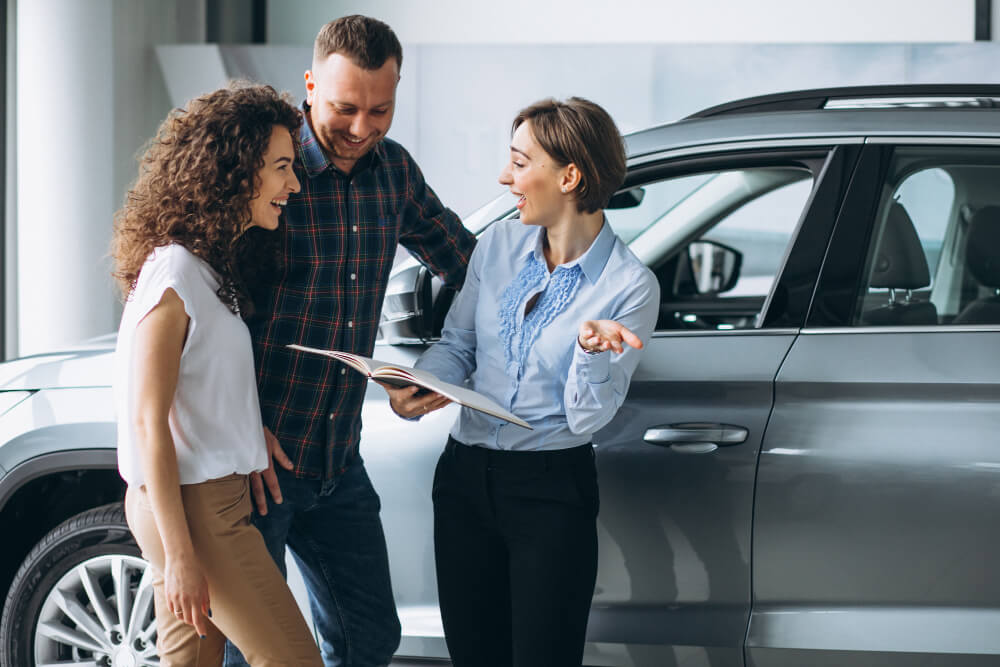 casal jovem falando com um vendedor numa loja de automóveis